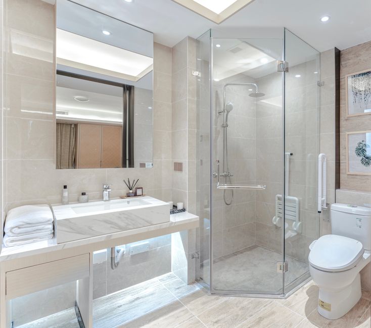 A stylish bathroom featuring a glass shower, marble sink, and elegant decor.